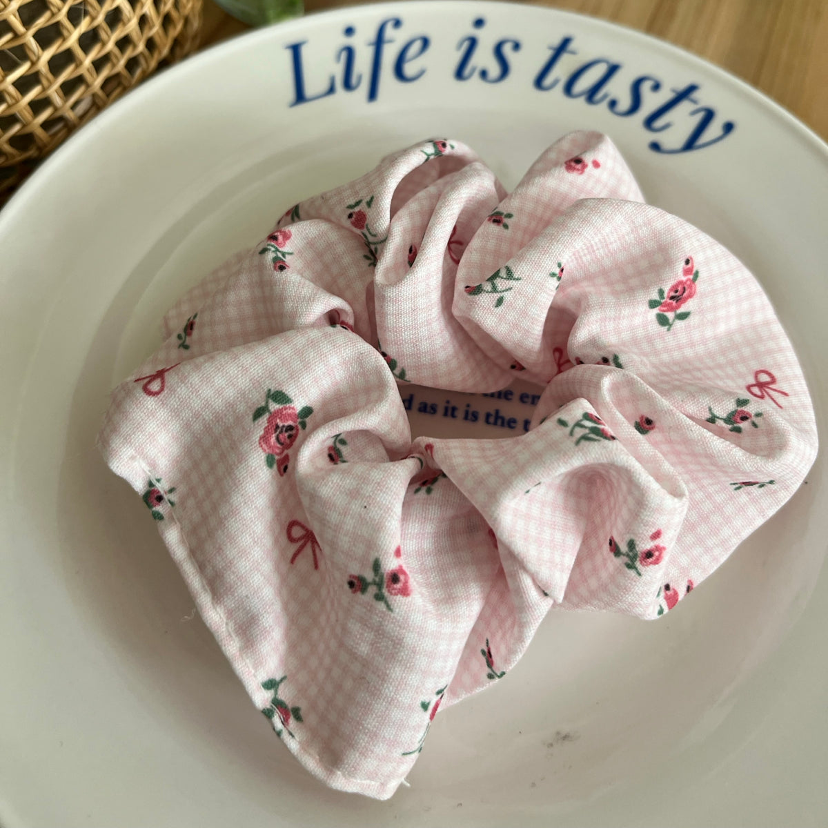 Pink scrunchie with floral pattern on a white plate with 'Life is tasty' text