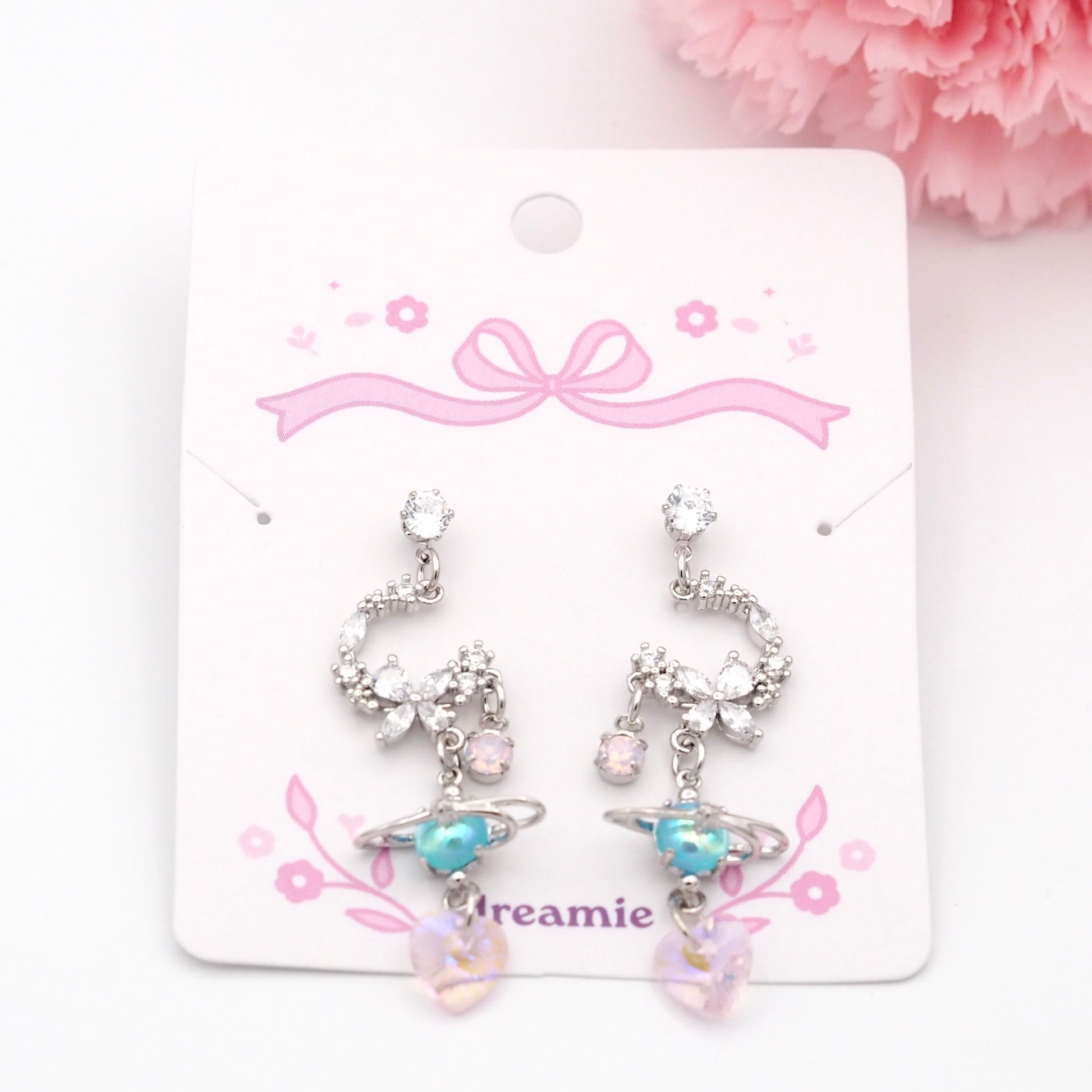 Pair of earrings on a 'Dreamie' branded card with pink flowers in the background
